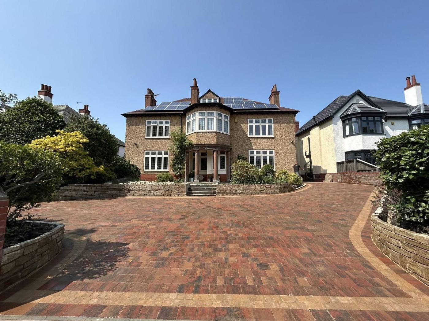 Large British house with a clean red brick paved driveway