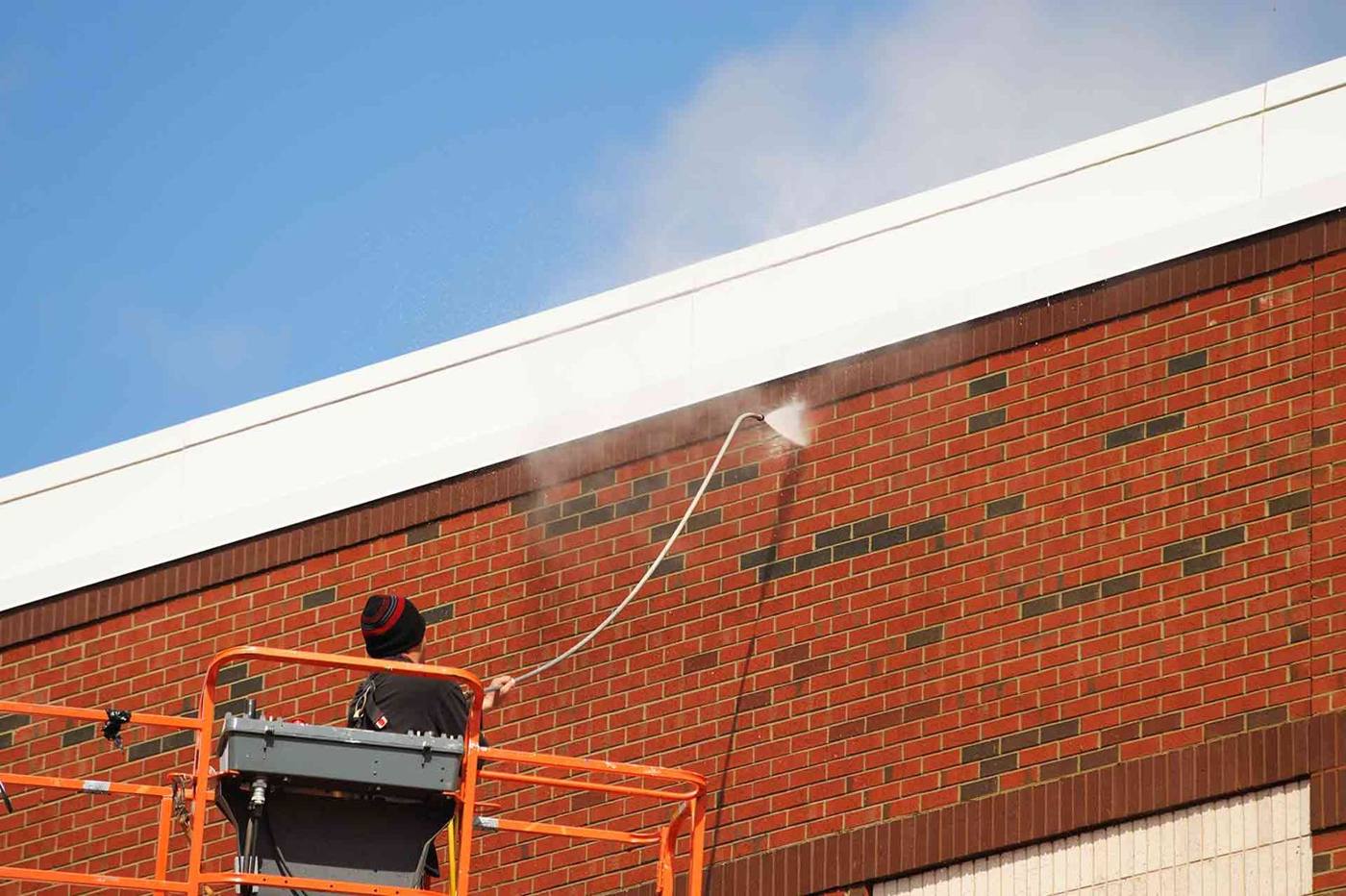 Jet washing a red brick wall